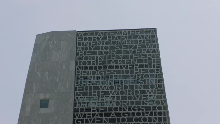 A low-angle static shot of the United States Courthouse in Salt Lake City, with its unique facade of cut-out words against an overcast sky