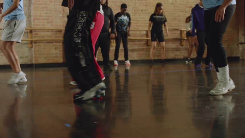 Low-angle view of dancers' feet moving in unison during a practice session in a dance studio