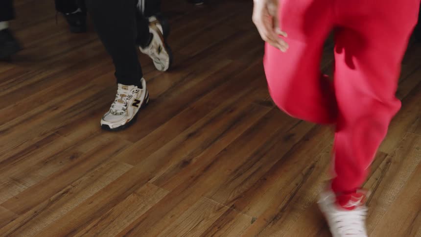 Close-up on the dancing feet of a group of young Black men before the camera tilts up to reveal them practicing a synchronized routine together