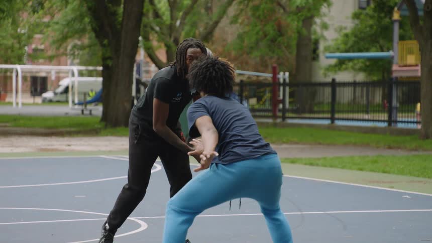 Slow motion shot of a young man with dreadlocks dribbling a basketball past his friends on an outdoor court
