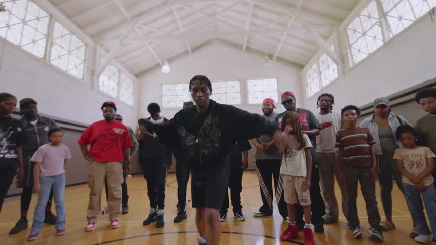 A talented dancer showcases impressive Chicago-style footwork for a crowd of onlookers in a community gymnasium