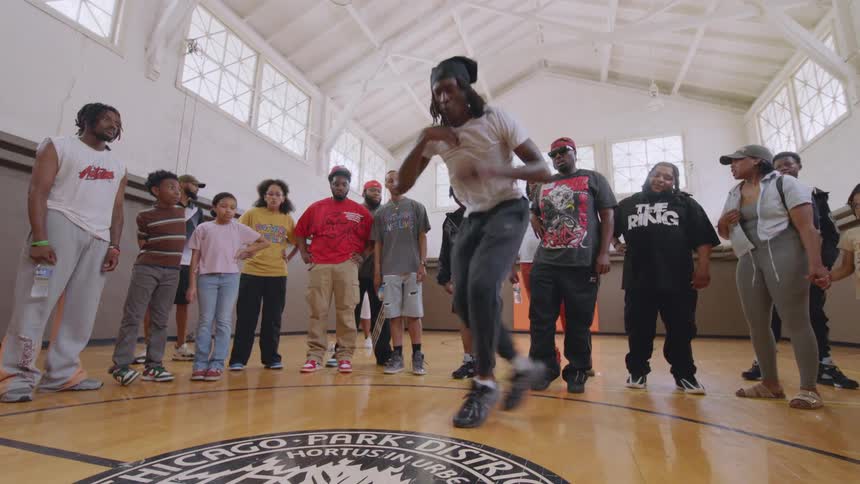 A talented Chicago Footwork dancer performs an energetic routine for a crowd in a community center gymnasium
