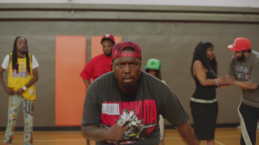 Close-up slow-motion shot of an energetic African American male dancer performing an intense footwork routine in a gymnasium