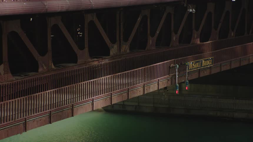Close up static night shot of pedestrians walking and jogging on the lower level of Chicago's iconic DuSable Bridge