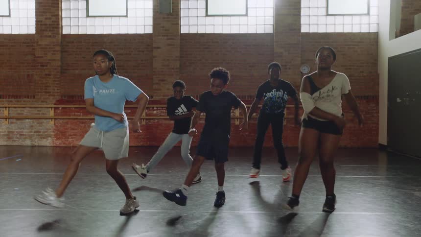A group of talented young dancers perfects their synchronized hip-hop routine in a spacious, naturally lit studio