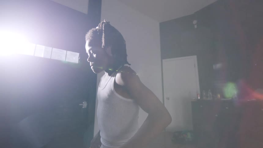 Slow motion shot of a young Black boy with headphones dancing with intense focus and passion in his room