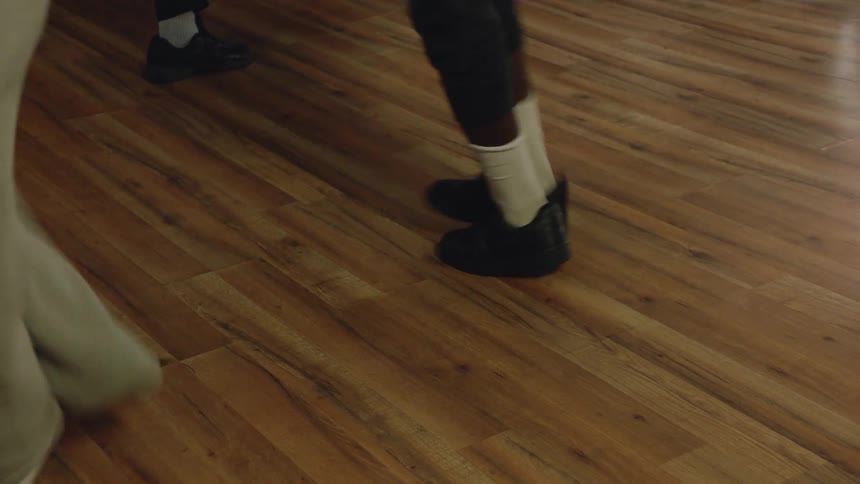 Low-angle shot of dancers' feet moving rhythmically in sneakers during a dance practice