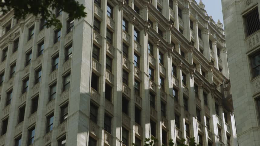 A static, low-angle shot captures the detailed facade of a classic, ornate high-rise building in a downtown city setting
