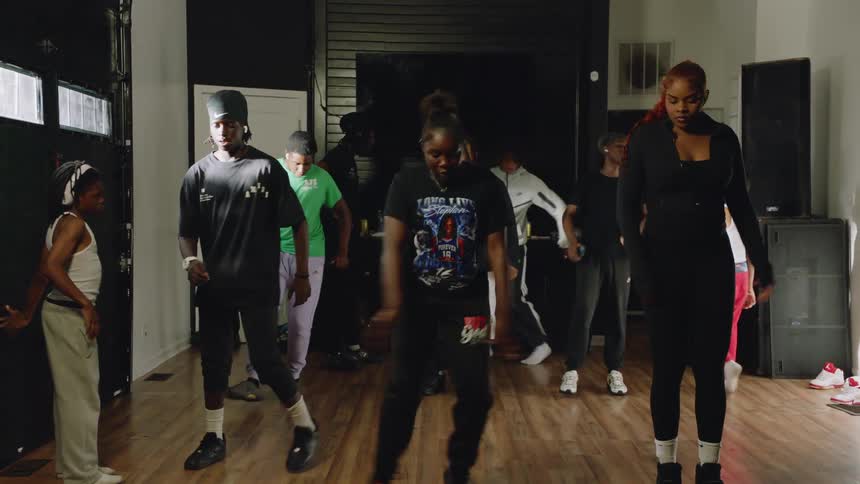 A group of young dancers in a studio practice a hip-hop routine together in slow motion
