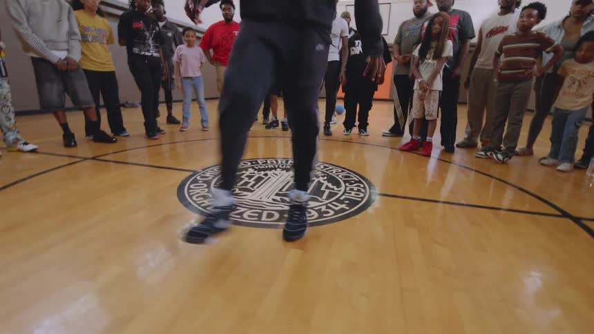 A young dancer showcases his impressive footwork skills in a dance cypher at a Chicago community center gymnasium