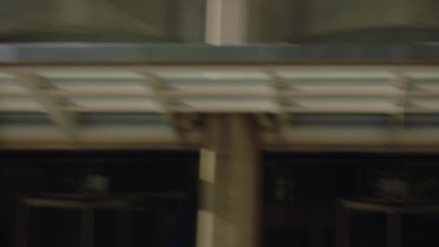 A fast-moving tracking shot from a vehicle captures the blurred cityscape of a downtown street during the day