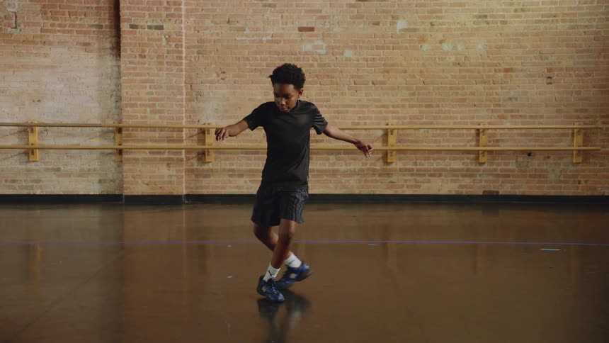 Slow motion of a young boy performing an intricate and focused dance routine in a studio