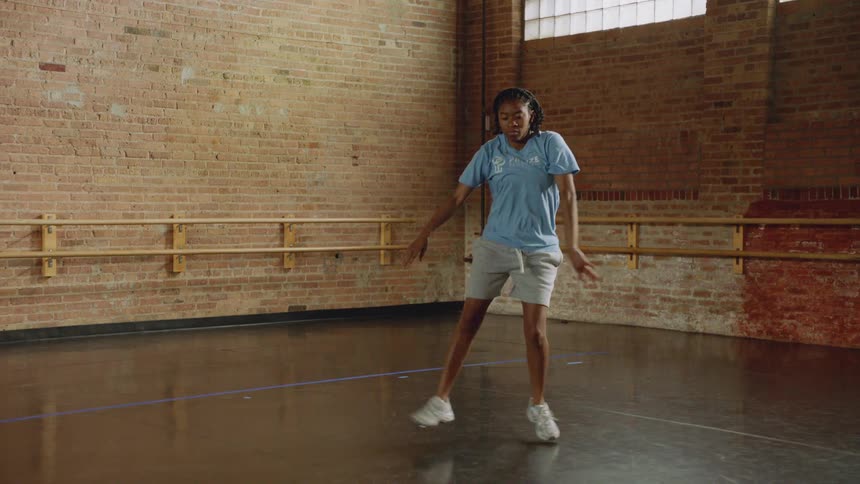 A talented young woman practices an energetic hip-hop routine in a dance studio in slow motion