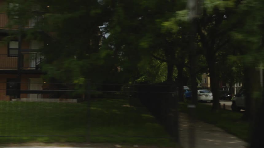 A slow drive through a quiet residential neighborhood, passing houses, apartments, and leafy green trees