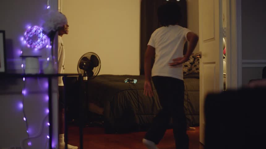 Two joyful young African American brothers in slow motion show off their dance moves for each other in their bedroom