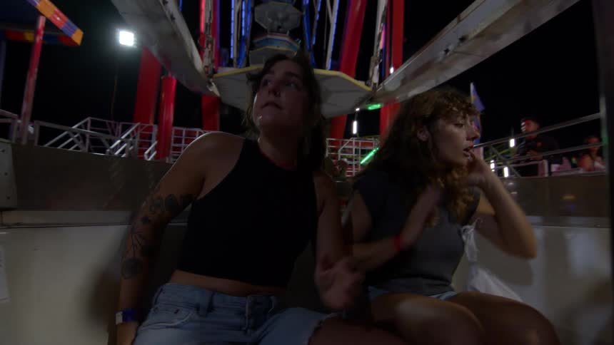 A group of friends spin around on a dizzying carnival ride at night, seen from a personal perspective