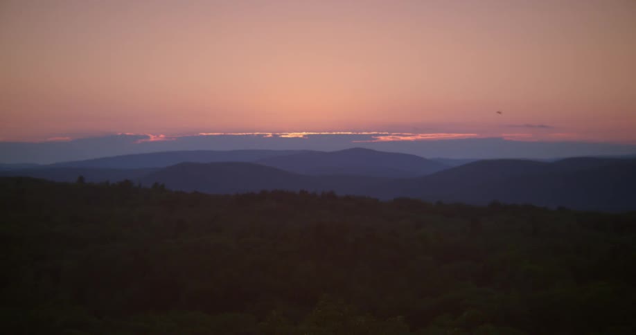 The sun rises over rolling hills