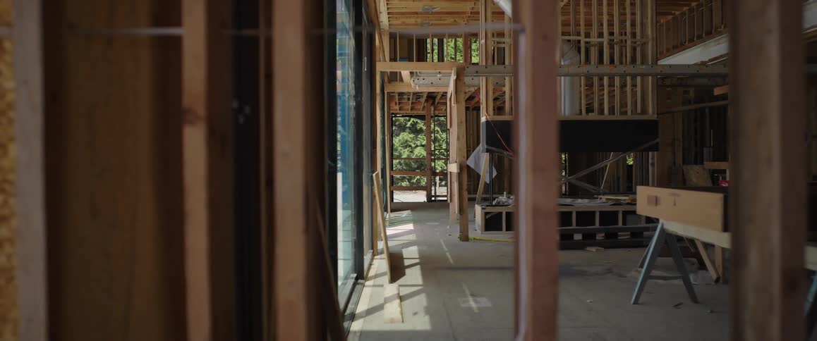 A slow dolly shot reveals the exposed wooden framing of a custom luxury home under construction