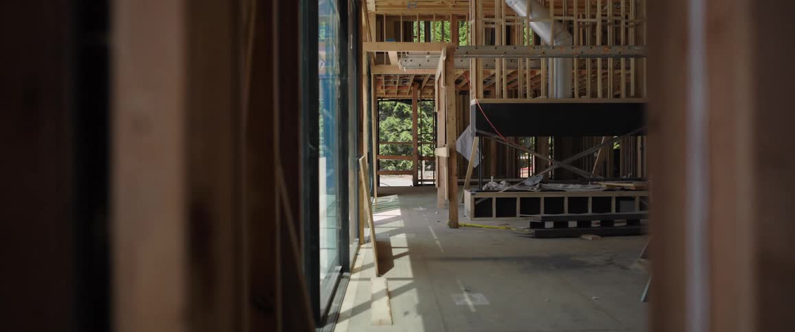 Slow dolly shot through the wooden frame reveals the interior of a modern home during construction
