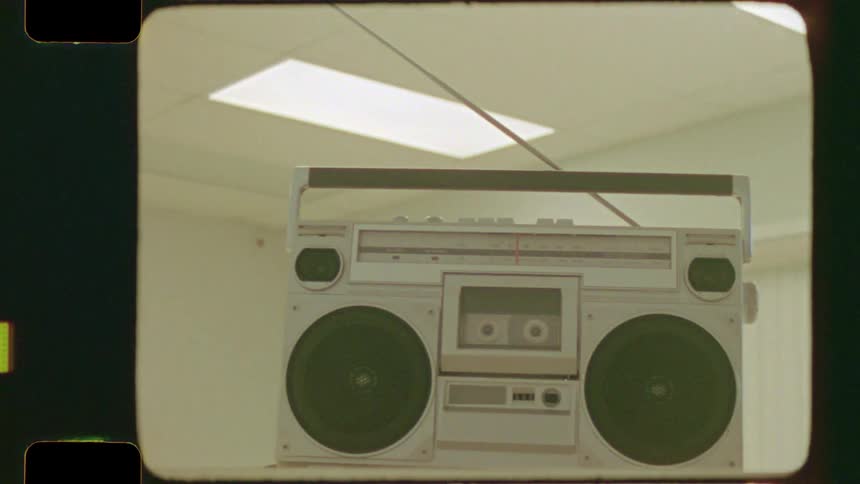 A vintage 1980s boombox with a cassette player sits in a room in this authentic super 8mm film