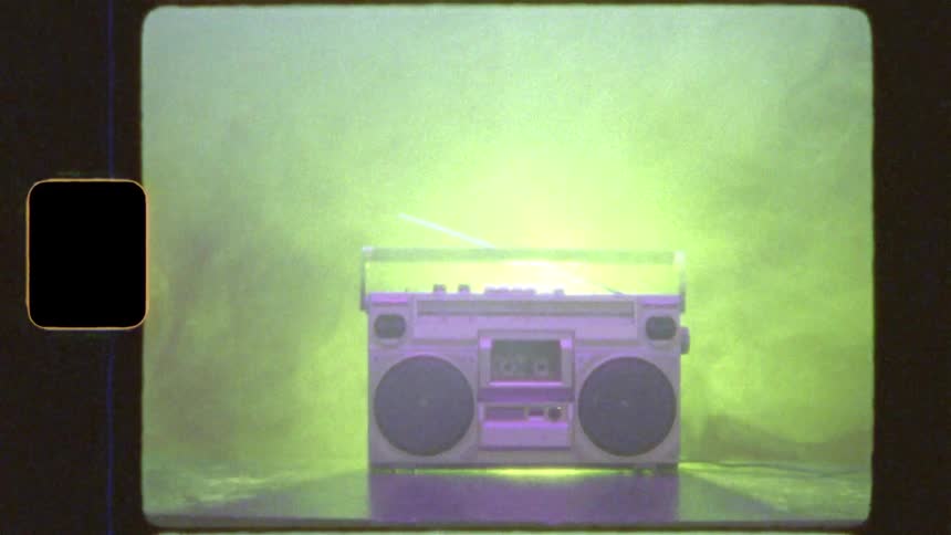 An iconic 80s boombox is bathed in colorful, flashing lights and smoke, with a vintage 8mm film effect