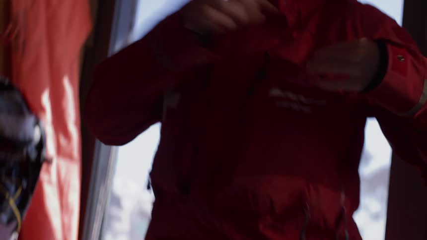 A female ski patroller prepares for her duties, checking a map before grabbing her radio and medical pack from a mountain hut