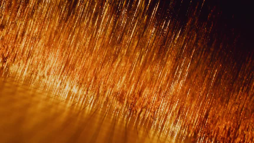 An extreme macro shot of shimmering golden threads or fibers creating a warm, abstract background
