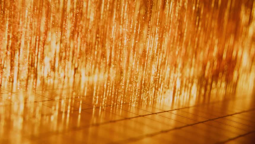 A macro shot of glowing golden threads shimmering and reflecting light, creating a luxurious abstract background