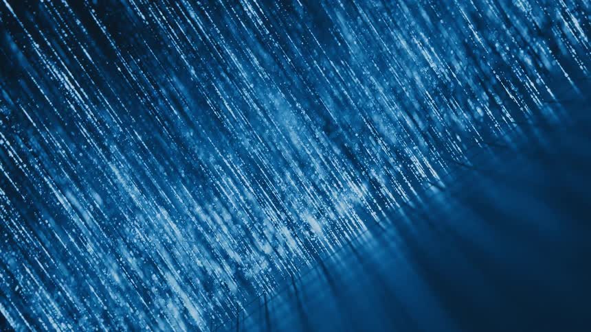 Abstract streaks of glowing blue light particles fall like digital rain against a dark background, creating a futuristic effect