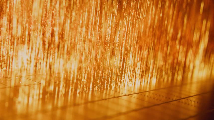 A mesmerizing macro shot of shimmering golden threads vibrating in the light on an industrial loom