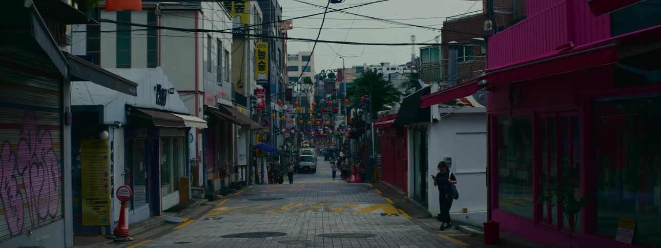 A quiet, decorated street in a city in South Korea on an overcast day with a few pedestrians walking