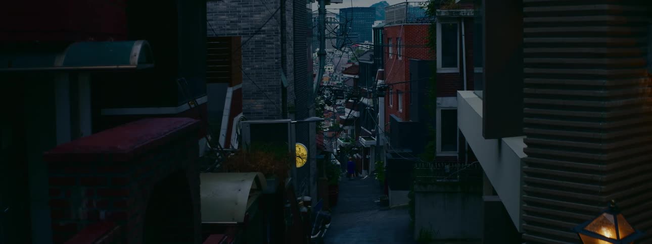 A static view looking down a narrow and steep urban alleyway in a residential area of Seoul at dusk