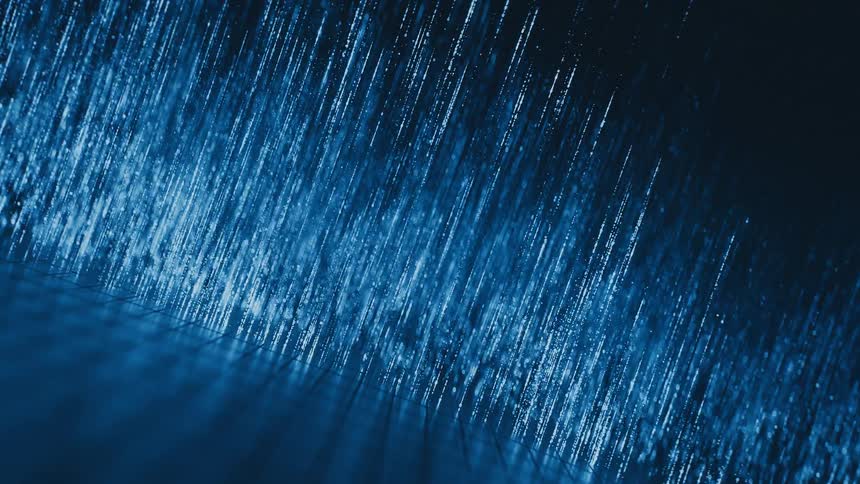 An abstract macro shot of glowing blue particles streaming downwards along fine lines like digital rain