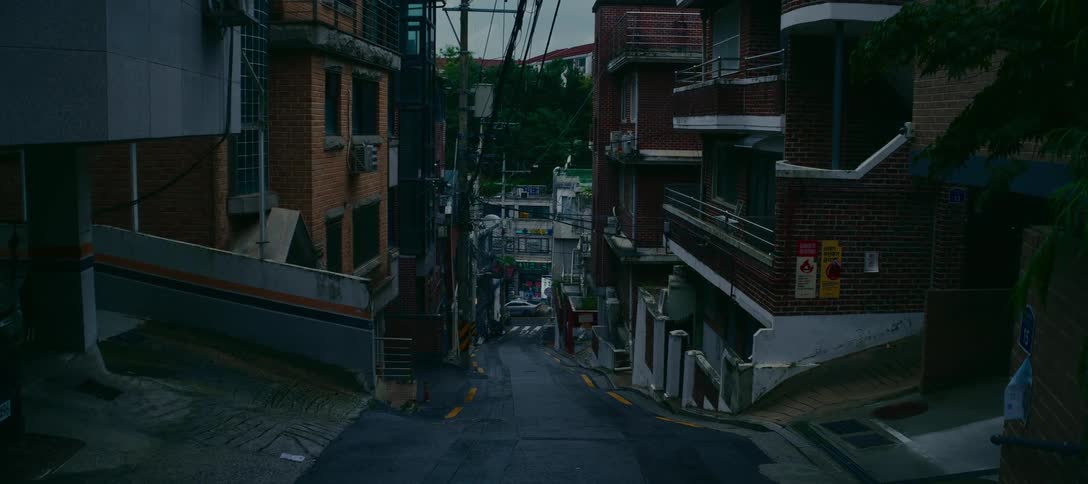 A static shot of a steep, empty back street in a dense residential neighborhood in Seoul, South Korea, on a gloomy day