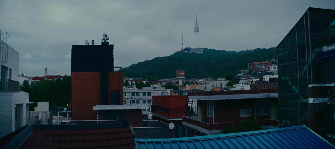 The iconic N Seoul Tower stands tall on a green hill overlooking the city of Seoul on a quiet, overcast day