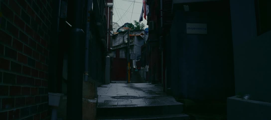 A gloomy and quiet view down a narrow, wet alleyway in an old urban neighborhood in South Korea