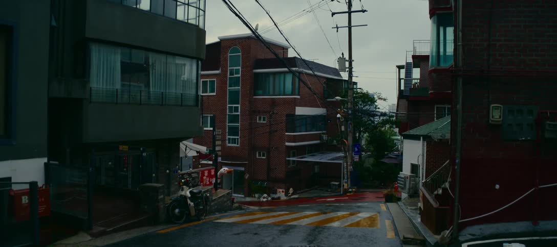A quiet, empty residential street corner in an Asian city on a gloomy, overcast day