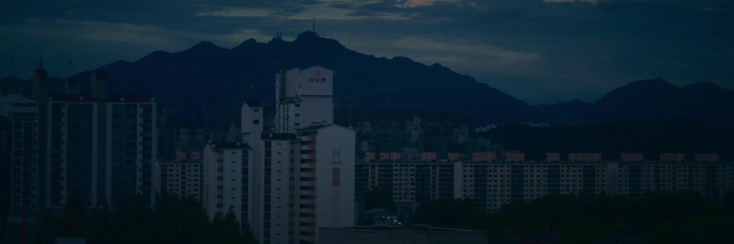 A still shot of an Asian city's high-rise apartment buildings and a distant mountain at dusk