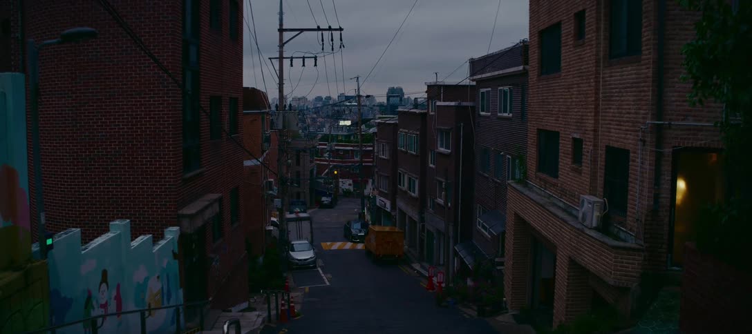 Twilight settles over a quiet, hilly residential street in a South Korean city