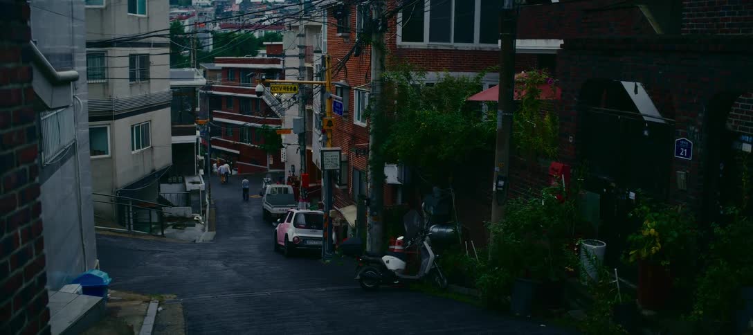 A static shot of a quiet, hilly residential street in a South Korean city on an overcast day