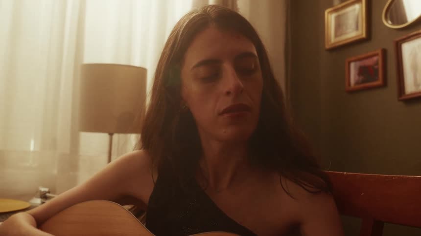Close-up of a female musician lost in the moment while playing her acoustic guitar in a warmly lit living room