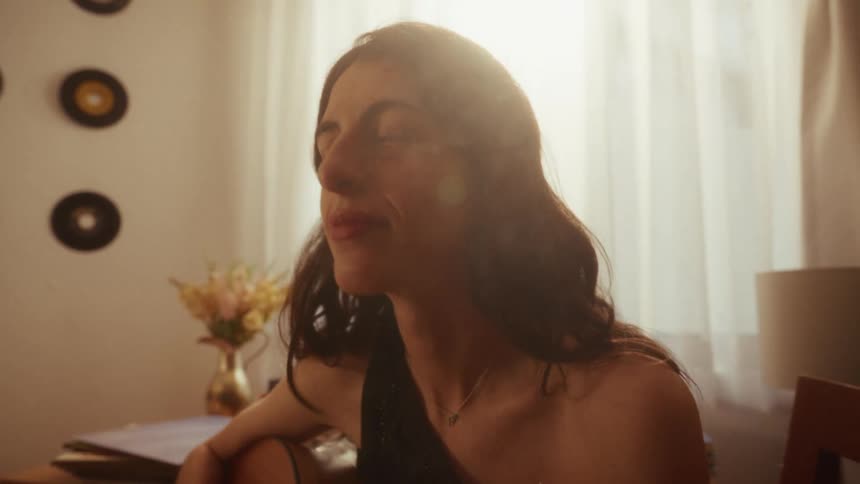 A musician gets lost in a moment of emotional reflection while playing the acoustic guitar in her sun-drenched room