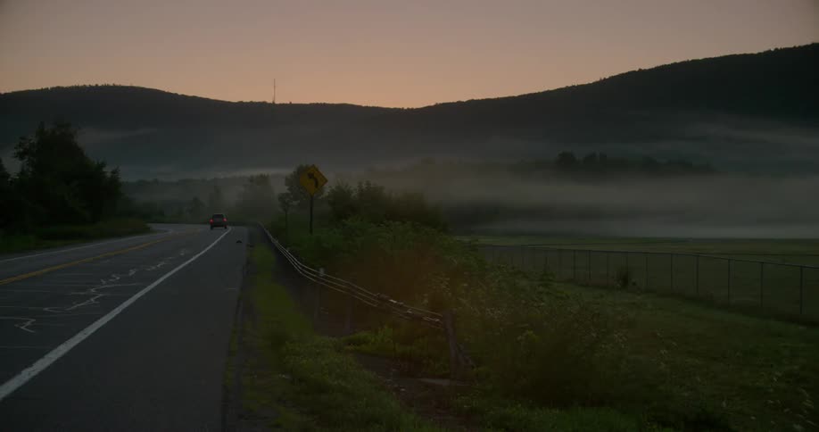 The road has fields covered with fog