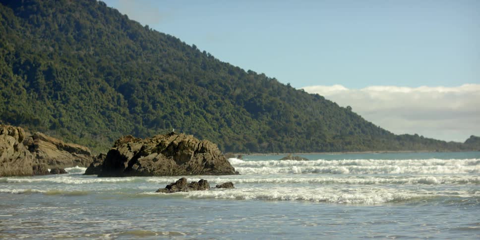 Waves roll onto a shore lined with rocks
