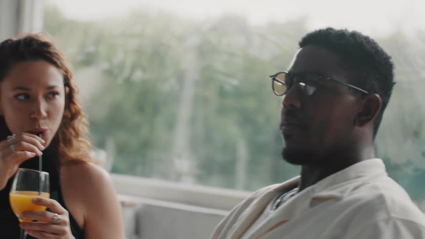 Close-up of a diverse young couple having a lively conversation over drinks in a cafe