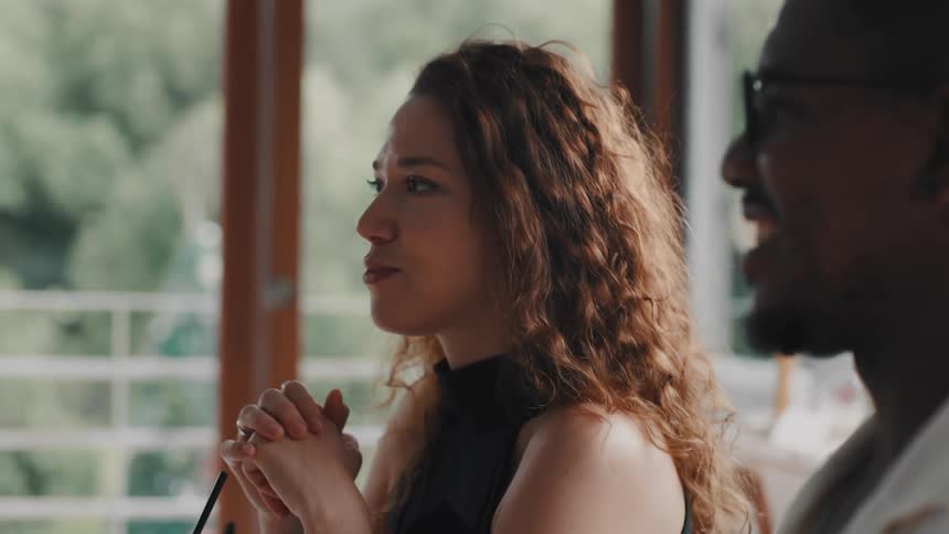 Slow motion shot of a woman with curly hair enjoying a meal and conversation with her partner at a bright cafe