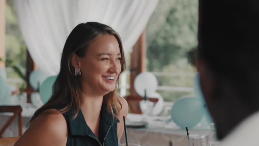 A joyful woman laughs and chats with her date while enjoying a meal together in a beautifully decorated restaurant