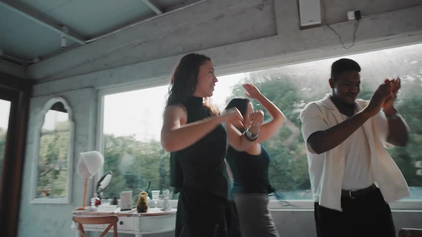 A diverse group of friends laugh and dance joyfully in slow motion at a sunlit party