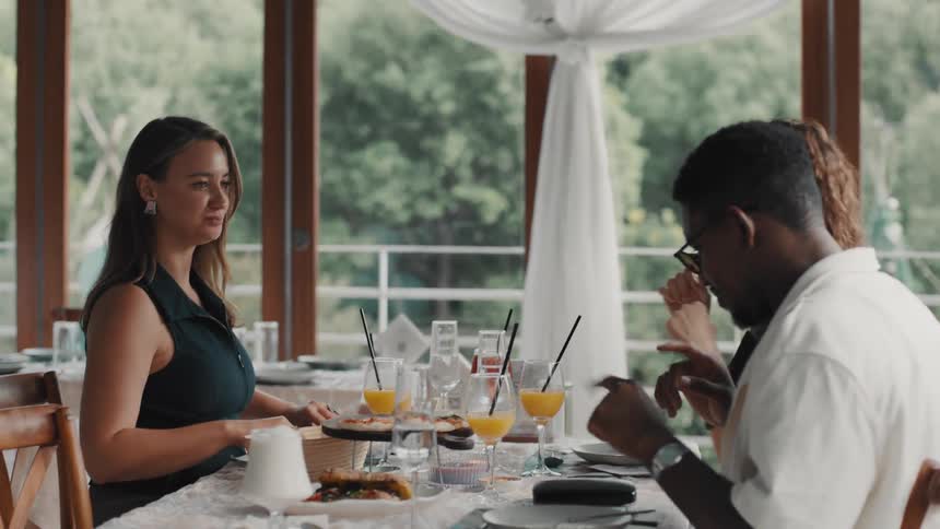 A group of young, multi-ethnic friends share a meal and animated conversation in a bright restaurant