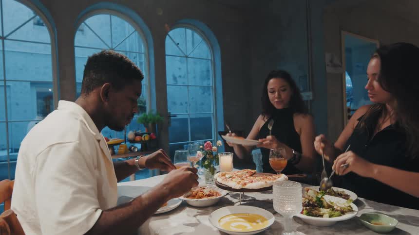 A diverse group of friends share a delicious meal and conversation during a candlelit dinner party